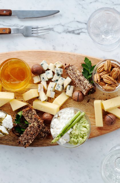 Assorted delicious cheese and nuts, bruschette with yogurt, pesto and bresaola, and a plate of spaghetti on the marble table