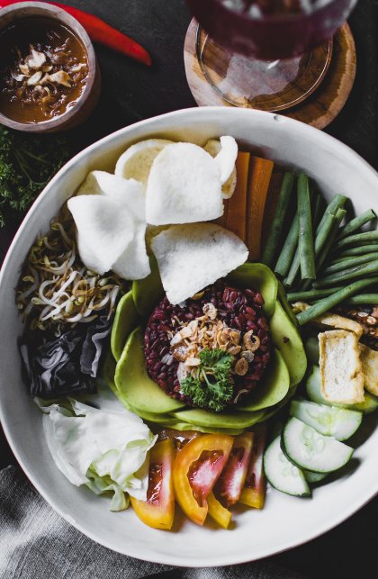 Indonesian vegan plate of vegetables cut in small pieces with quinoa and komosa served with sauce