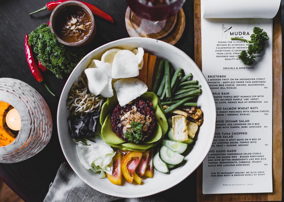 Indonesian vegan plate of vegetables cut in small pieces with quinoa and komosa served with sauce